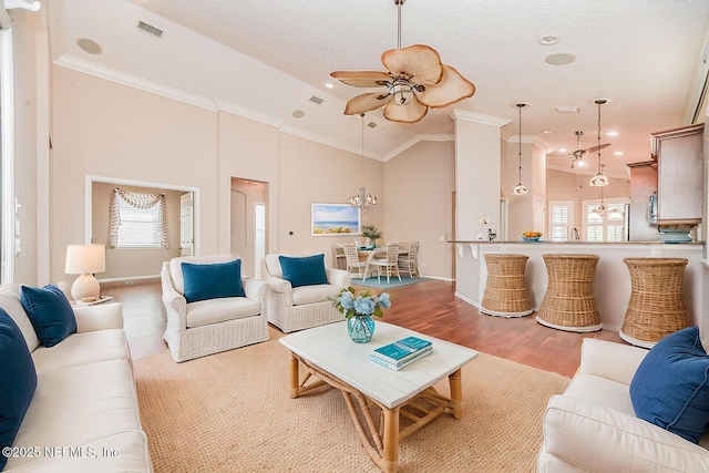 living room featuring crown molding, high vaulted ceiling, light hardwood / wood-style flooring, a textured ceiling, and ceiling fan