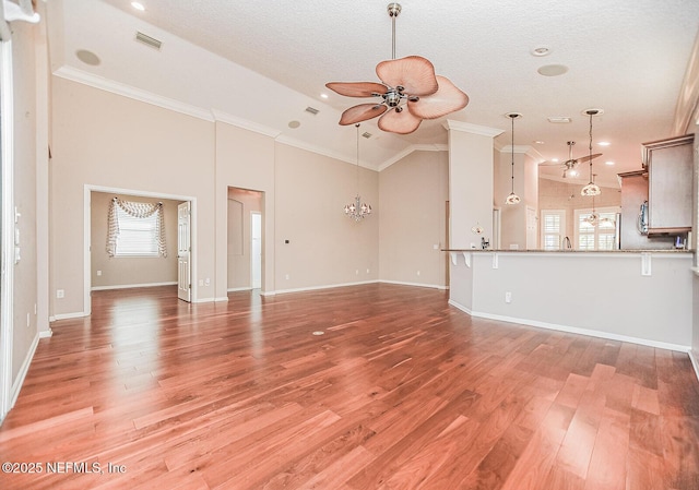 unfurnished living room featuring crown molding, light hardwood / wood-style flooring, high vaulted ceiling, a textured ceiling, and ceiling fan with notable chandelier