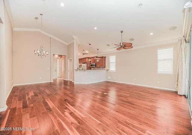 unfurnished living room featuring hardwood / wood-style floors, ornamental molding, lofted ceiling, and ceiling fan with notable chandelier