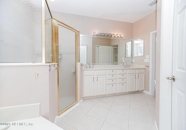 bathroom with vanity, a textured ceiling, an enclosed shower, and tile patterned flooring