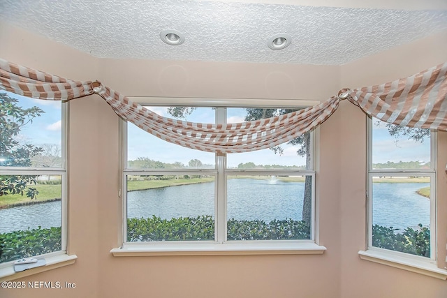 interior details featuring a water view and a textured ceiling