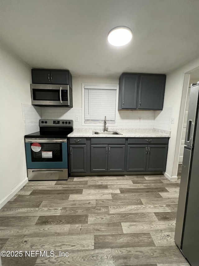 kitchen with sink, stainless steel appliances, light hardwood / wood-style floors, and tasteful backsplash