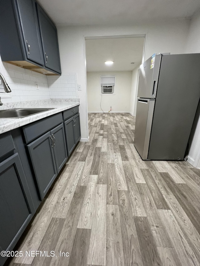 kitchen with sink, backsplash, gray cabinets, light hardwood / wood-style floors, and stainless steel refrigerator