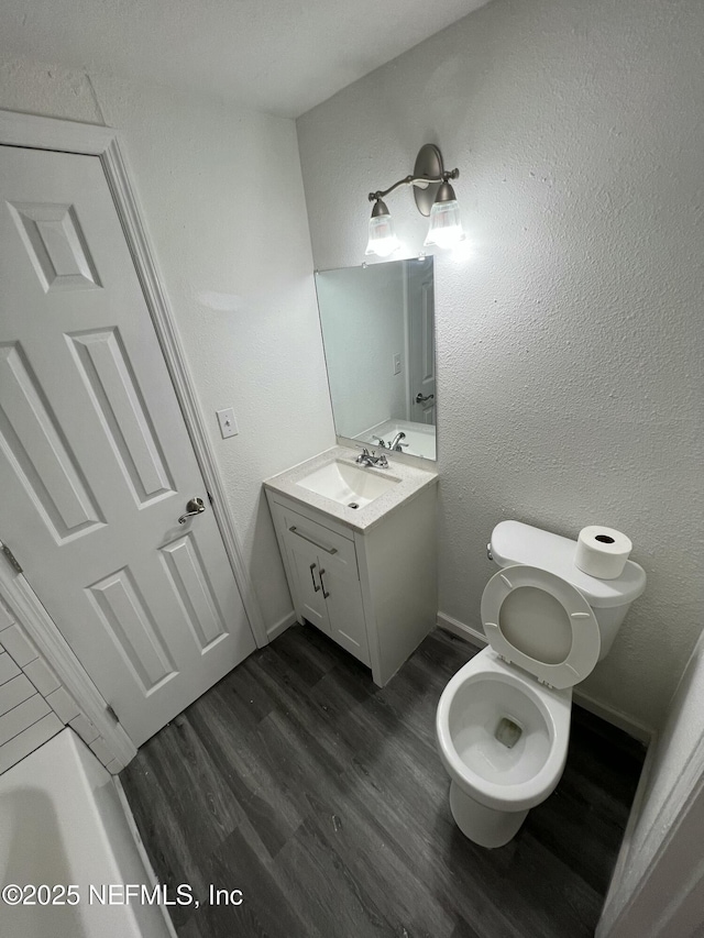 bathroom with hardwood / wood-style flooring, toilet, and vanity