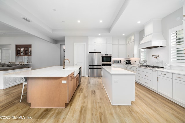 kitchen featuring white cabinetry, custom range hood, a spacious island, and appliances with stainless steel finishes