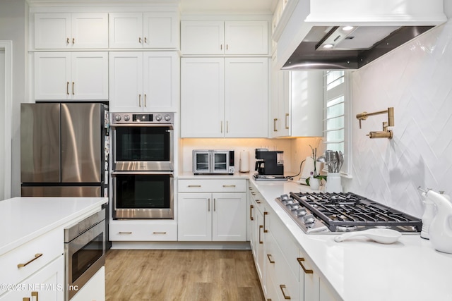 kitchen with light hardwood / wood-style flooring, backsplash, stainless steel appliances, white cabinets, and custom exhaust hood