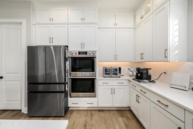 kitchen featuring stainless steel appliances, white cabinets, light stone counters, and light hardwood / wood-style flooring