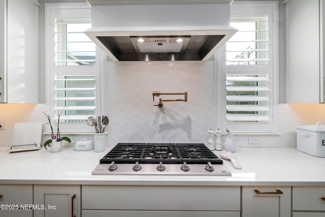 kitchen with stainless steel gas cooktop, custom range hood, and backsplash