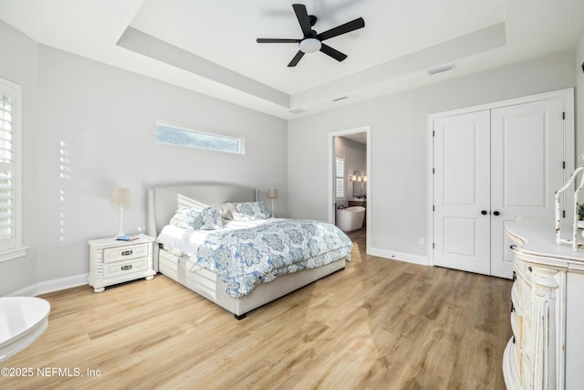 bedroom with a raised ceiling, wood-type flooring, ceiling fan, and a closet