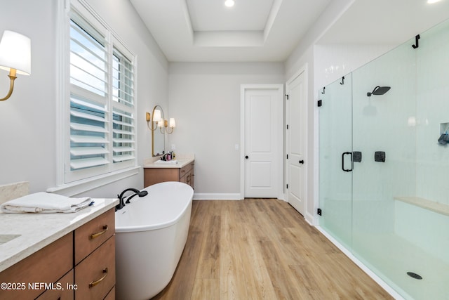 bathroom featuring a raised ceiling, vanity, separate shower and tub, and hardwood / wood-style flooring