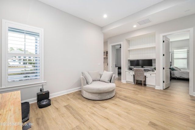 living area with plenty of natural light, built in desk, and light hardwood / wood-style floors