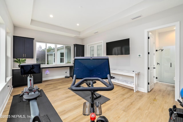 exercise area featuring light hardwood / wood-style floors and a raised ceiling