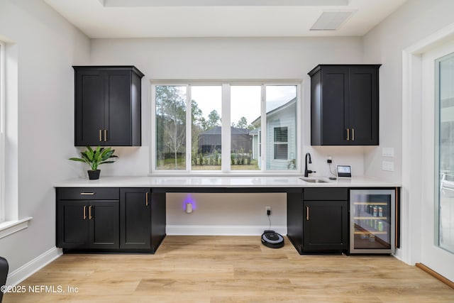 bar featuring beverage cooler, light hardwood / wood-style floors, and sink