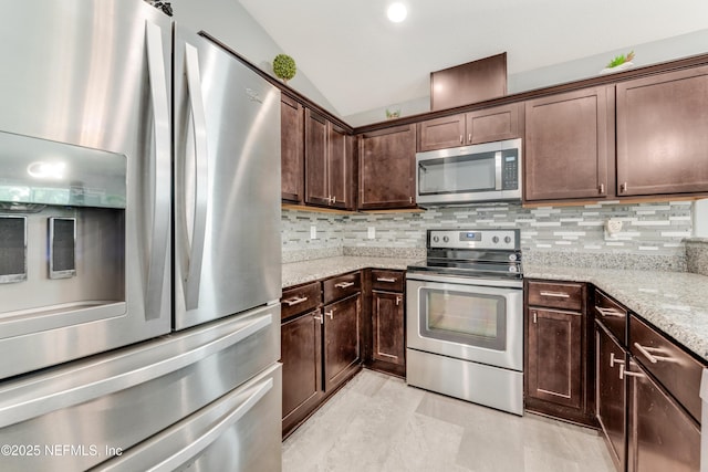 kitchen featuring stainless steel appliances, dark brown cabinets, light stone counters, and decorative backsplash