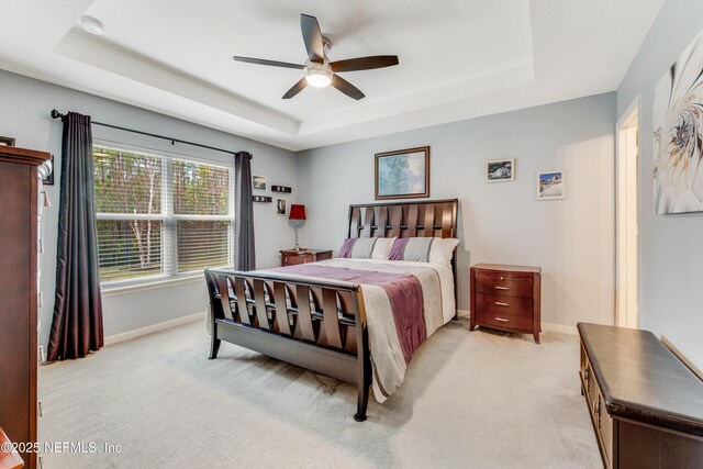 carpeted bedroom featuring ceiling fan and a tray ceiling