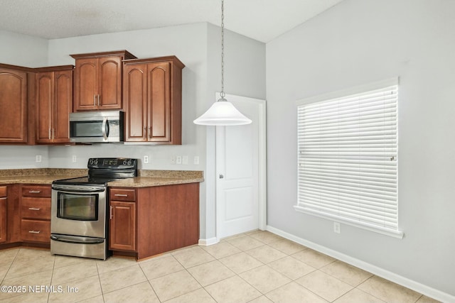 kitchen with decorative light fixtures, light tile patterned flooring, and appliances with stainless steel finishes