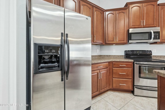 kitchen with stone countertops, light tile patterned floors, and stainless steel appliances