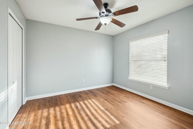 unfurnished bedroom with ceiling fan, multiple windows, a closet, and light wood-type flooring