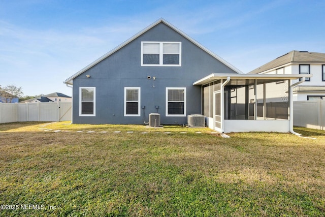 back of house featuring central air condition unit, a sunroom, and a yard