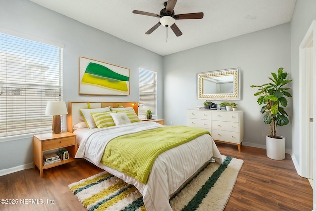 bedroom featuring ceiling fan, dark wood-type flooring, and multiple windows