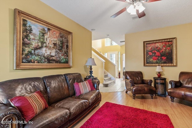 living room with ceiling fan, a textured ceiling, and light hardwood / wood-style floors