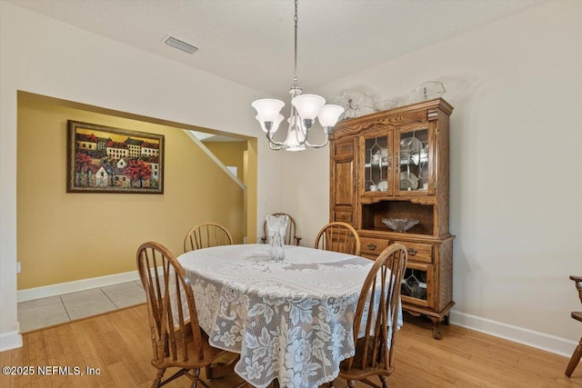 dining area with light hardwood / wood-style flooring and a notable chandelier