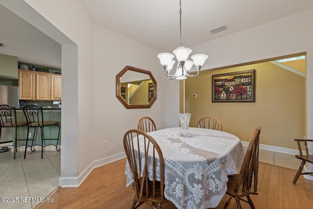 dining space with a chandelier and light hardwood / wood-style flooring