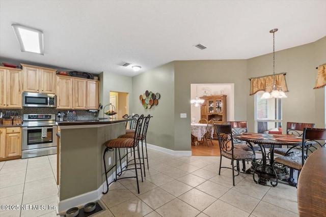 kitchen featuring tasteful backsplash, light tile patterned flooring, light brown cabinets, and appliances with stainless steel finishes