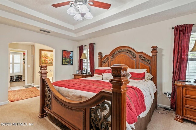 carpeted bedroom with a raised ceiling and ceiling fan