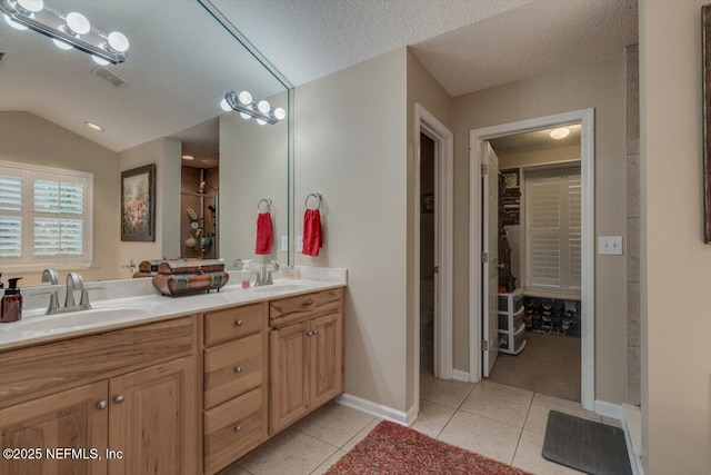 bathroom featuring lofted ceiling, vanity, tile patterned flooring, and a textured ceiling