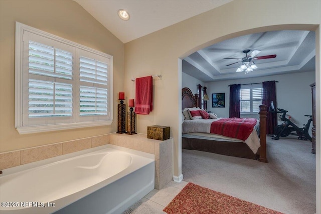 bathroom with lofted ceiling, ceiling fan, tile patterned flooring, and a bathing tub