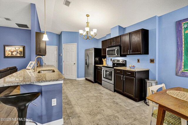 kitchen featuring a breakfast bar area, dark brown cabinetry, a sink, visible vents, and appliances with stainless steel finishes