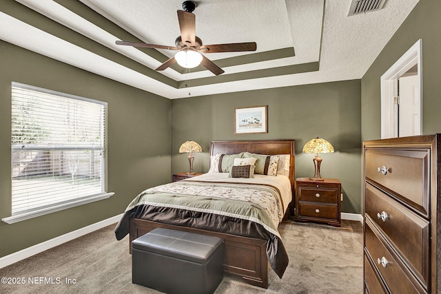 carpeted bedroom featuring baseboards, visible vents, a raised ceiling, and a textured ceiling