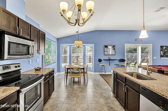 kitchen with lofted ceiling, stainless steel appliances, a sink, dark brown cabinets, and pendant lighting