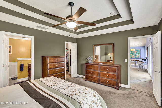 bedroom with carpet floors, visible vents, a tray ceiling, and a closet