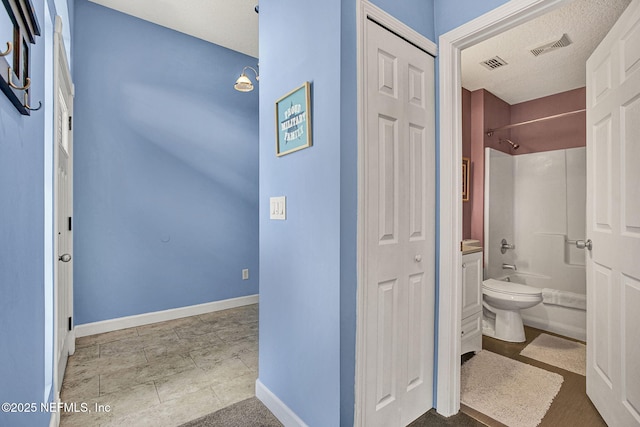 bathroom featuring toilet, shower / washtub combination, visible vents, and baseboards