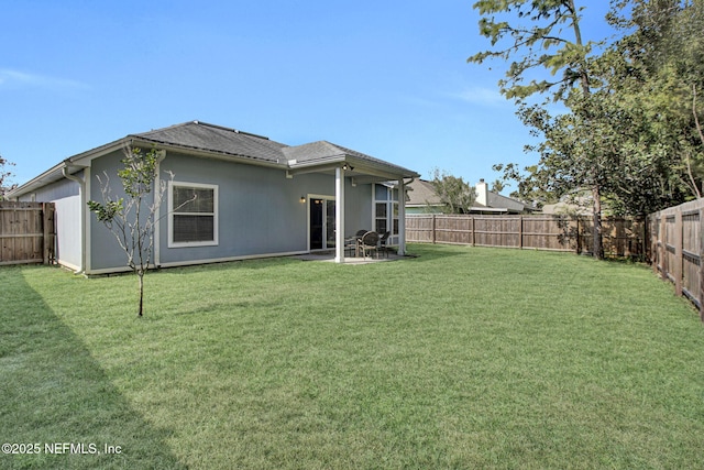 rear view of house featuring a fenced backyard, a yard, and a patio