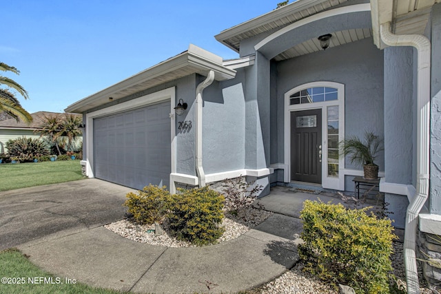 property entrance featuring a garage, driveway, and stucco siding