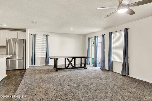 unfurnished room with ceiling fan, a textured ceiling, and dark colored carpet