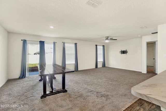 interior space with ceiling fan, a textured ceiling, and dark colored carpet