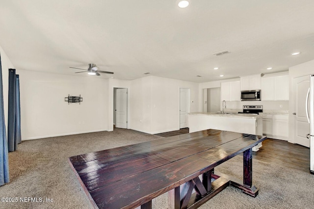 dining space with ceiling fan, sink, and dark colored carpet