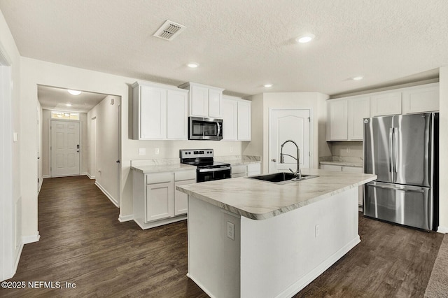 kitchen featuring sink, white cabinets, appliances with stainless steel finishes, and an island with sink