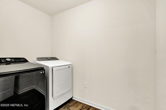 clothes washing area with washing machine and dryer and dark hardwood / wood-style floors