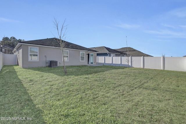 rear view of property featuring a lawn and central AC unit