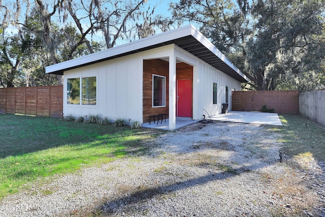 view of side of property featuring a lawn and a patio