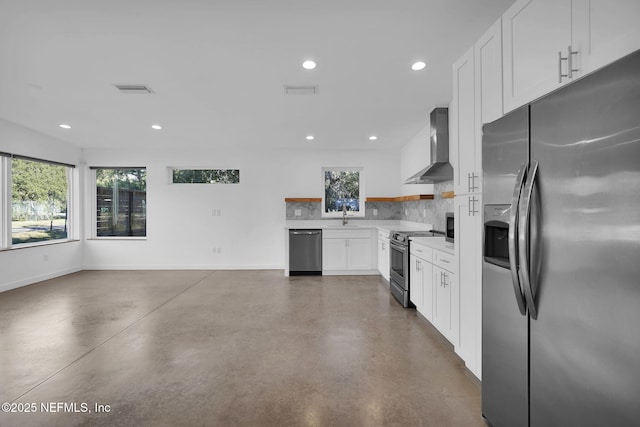 kitchen with appliances with stainless steel finishes, sink, backsplash, white cabinetry, and wall chimney range hood