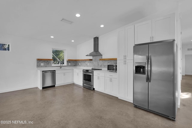 kitchen with appliances with stainless steel finishes, wall chimney exhaust hood, sink, white cabinetry, and decorative backsplash