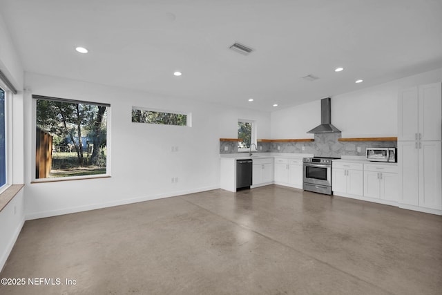 kitchen featuring white cabinets, appliances with stainless steel finishes, wall chimney exhaust hood, tasteful backsplash, and sink