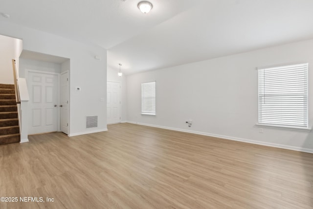 spare room featuring vaulted ceiling and light hardwood / wood-style floors