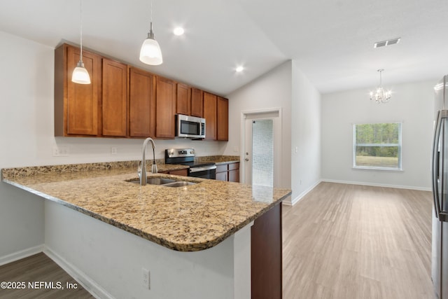 kitchen featuring appliances with stainless steel finishes, kitchen peninsula, and decorative light fixtures